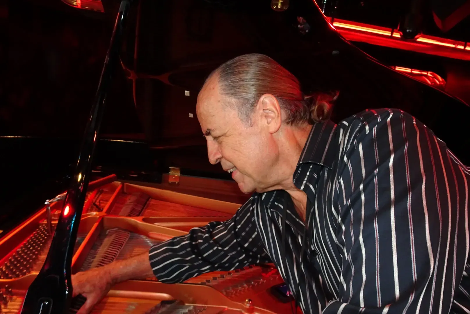 Marty Karmiol performing voicing adjustments inside a grand piano